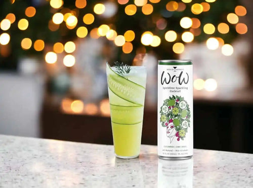 A tall glass of a light green beverage garnished with cucumber slices and a sprig of dill, next to a matching can.